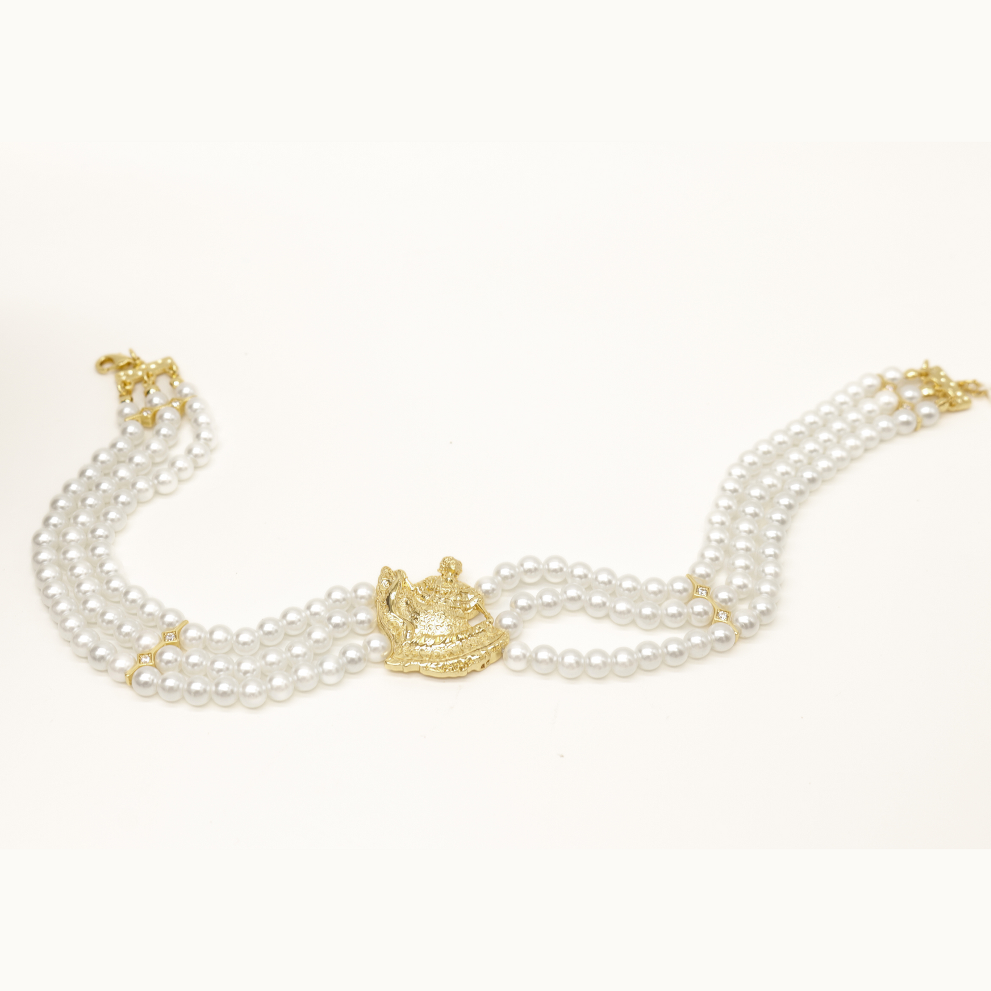 imitation pearl choker with gold plated pollera dancer pendant laid flat on table